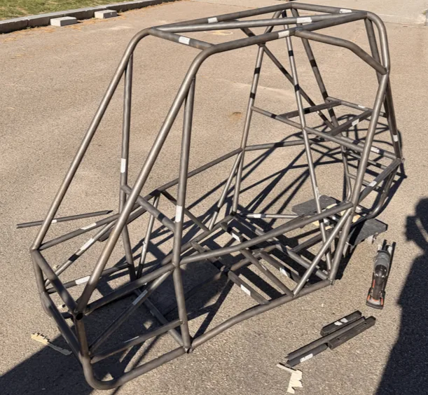 The fully welded bare-steel tubular space-frame chassis standing outdoors on asphalt