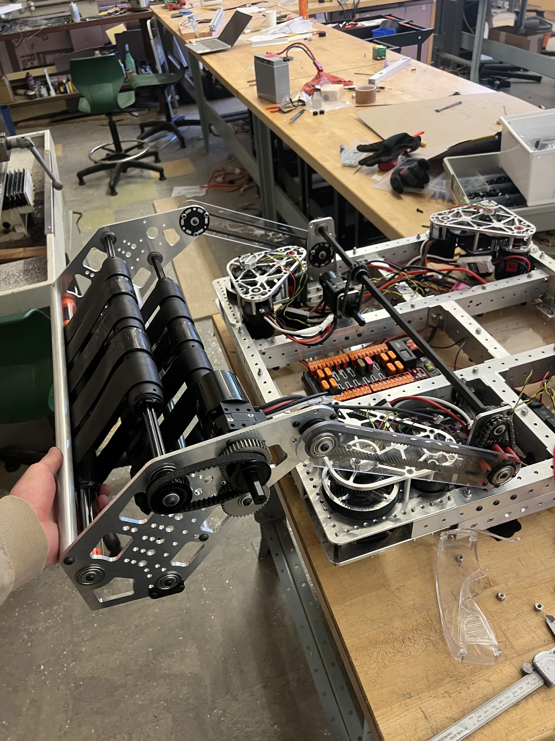 The 2024 intake deployed from the robot: black polyurethane belts on polycarbonate arms with a chain drive, photographed on the workshop floor