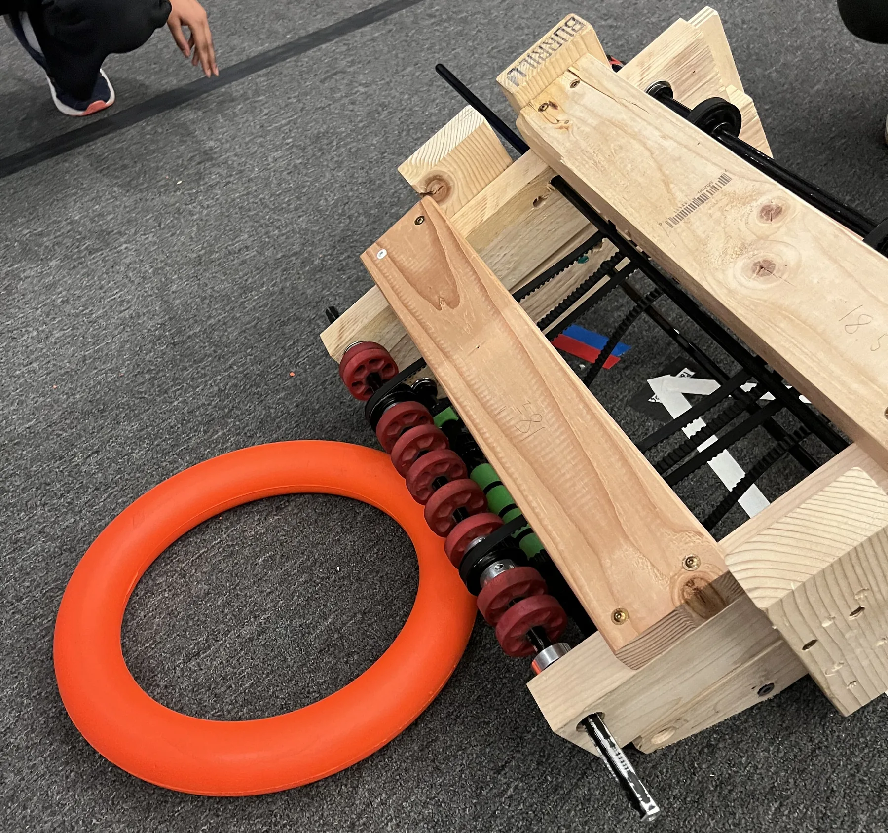 Intake V1: a wooden prototype frame with red rubber wheels next to an orange foam ring
