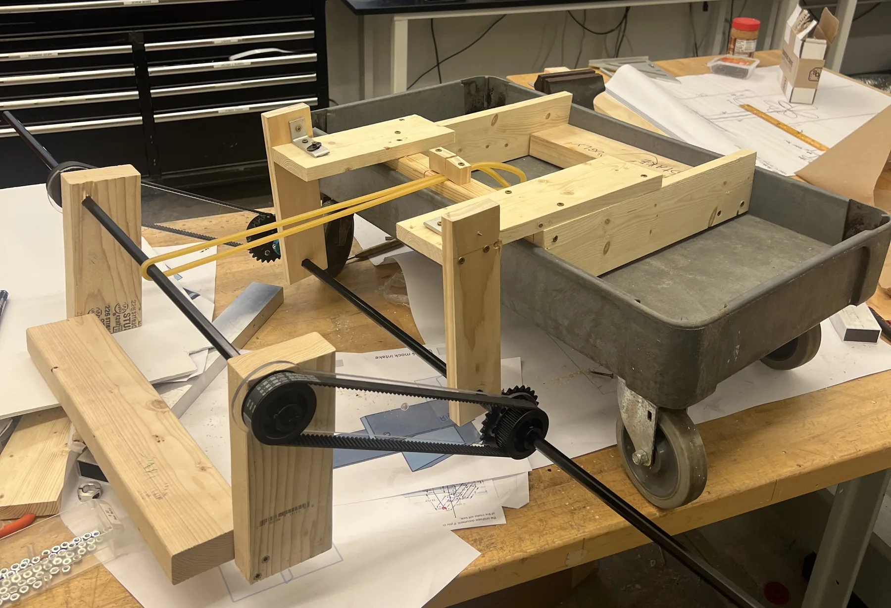 Intake V3: wooden arm linkage prototype with belts on a workbench
