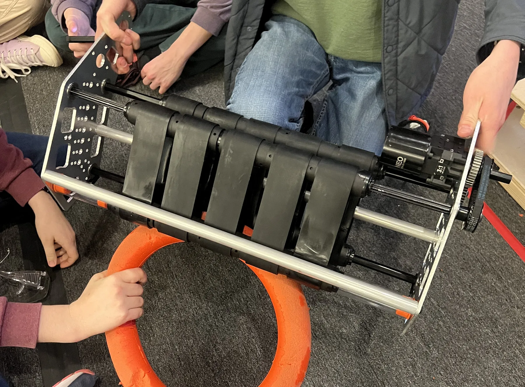 Intake V5 held by team members, showing ten short belts picking up an orange note