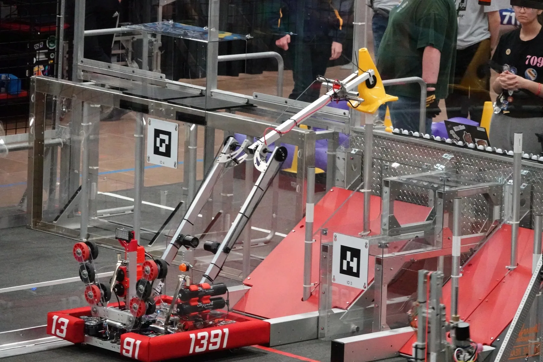 The 2023 robot BAMI with red bumpers numbered 1391 on the competition field, its double-jointed arm extended upward toward the scoring grid