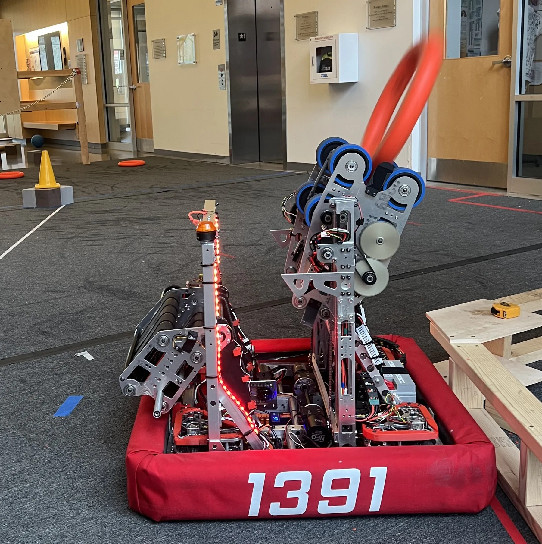 The 1391 robot launching an orange note from its shooter during indoor testing, the note blurred in the air above it