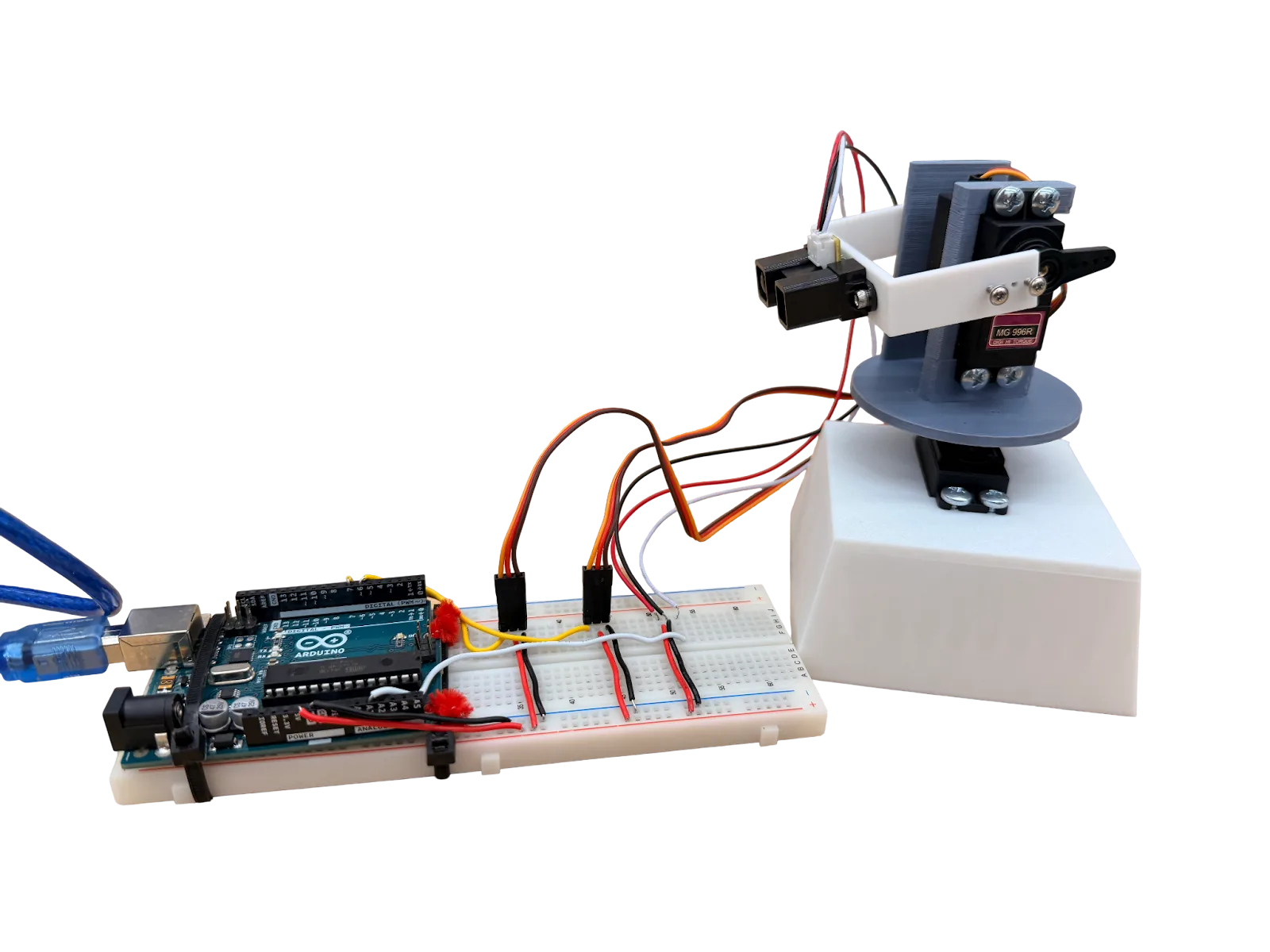 The completed 3D scanner: an Arduino Uno on a breadboard wired to a pan-and-tilt mount with an MG996R servo and a Sharp infrared distance sensor on a white 3D-printed base