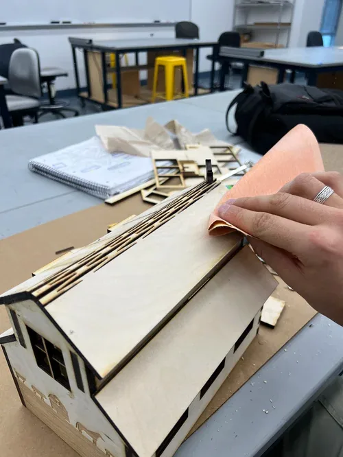 Sanding the plywood roof panel by hand on the assembled barn