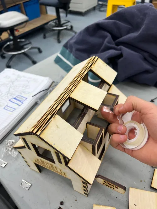 Attaching the roof to the barn with a roll of tape in hand