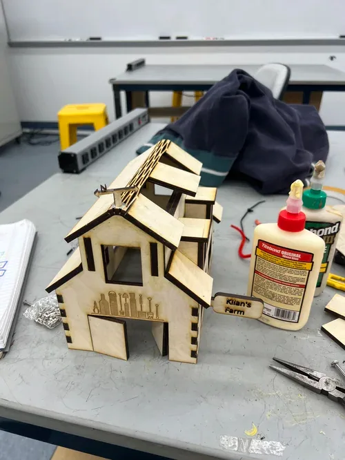 Nearly finished barn with the 'Kilan's Farm' sign fitted, wood glue and pliers beside it