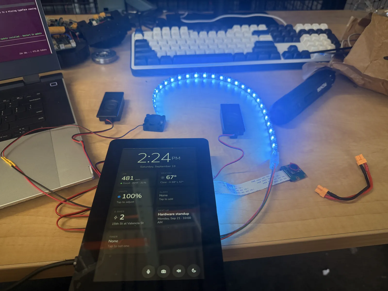 The external WS2812B LED strip lit blue on the desk next to the display showing the home screen