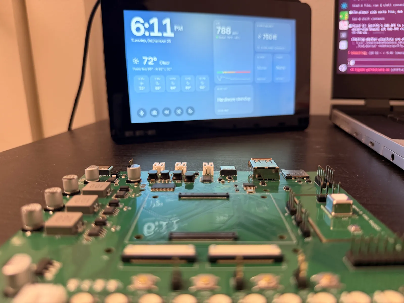 The bare rev A board in the foreground with the finished HomeDeck device behind it on the desk